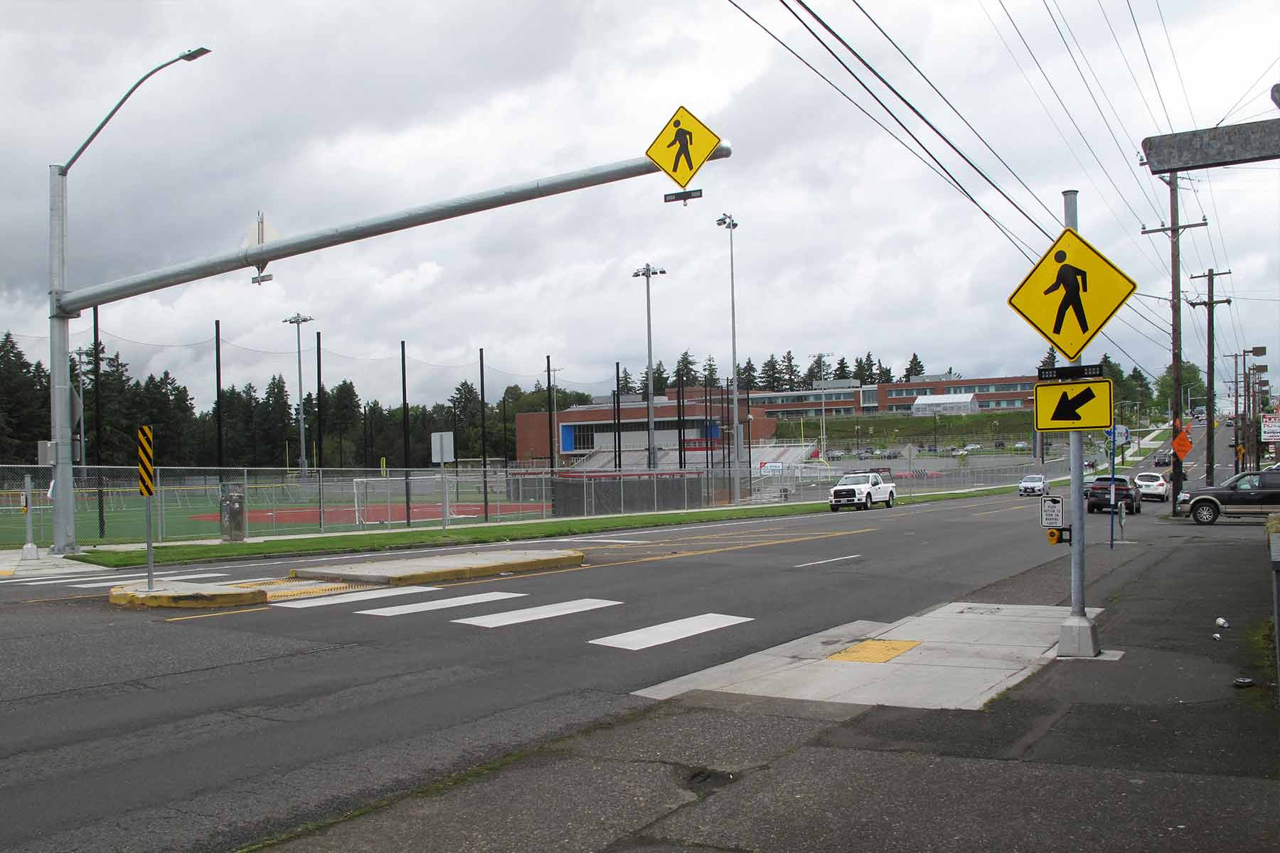 Crosswalk with two pedestrian signs with flashing yellow lights.